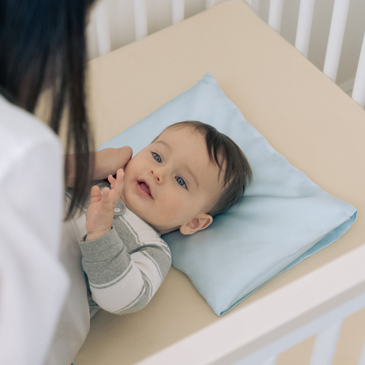Premium 6A silk baby pillow in baby blue styled on a cozy nursery bed, smooth, breathable, vegan and sustainable.