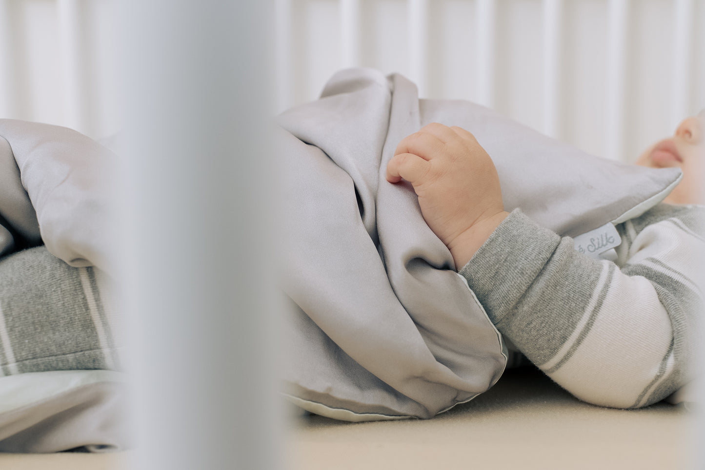 Premium 6A silk baby blanket in baby pink styled on a cozy nursery bed, smooth, breathable, vegan and sustainable.