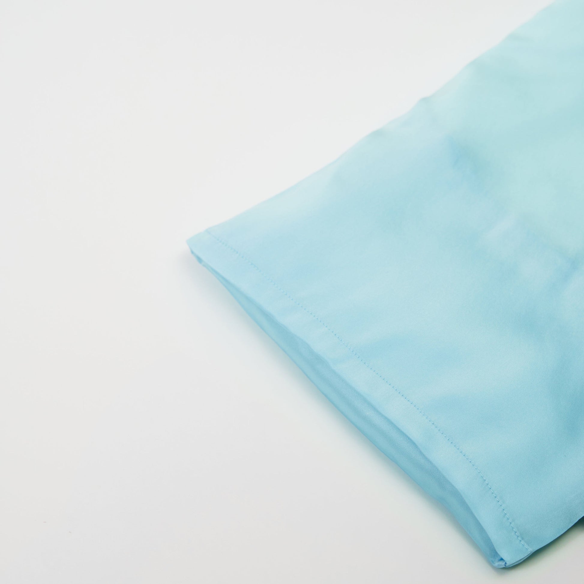 Close-up of premium 6A silk texture on a baby blue pillow, ultra-soft, breathable and eco-friendly.