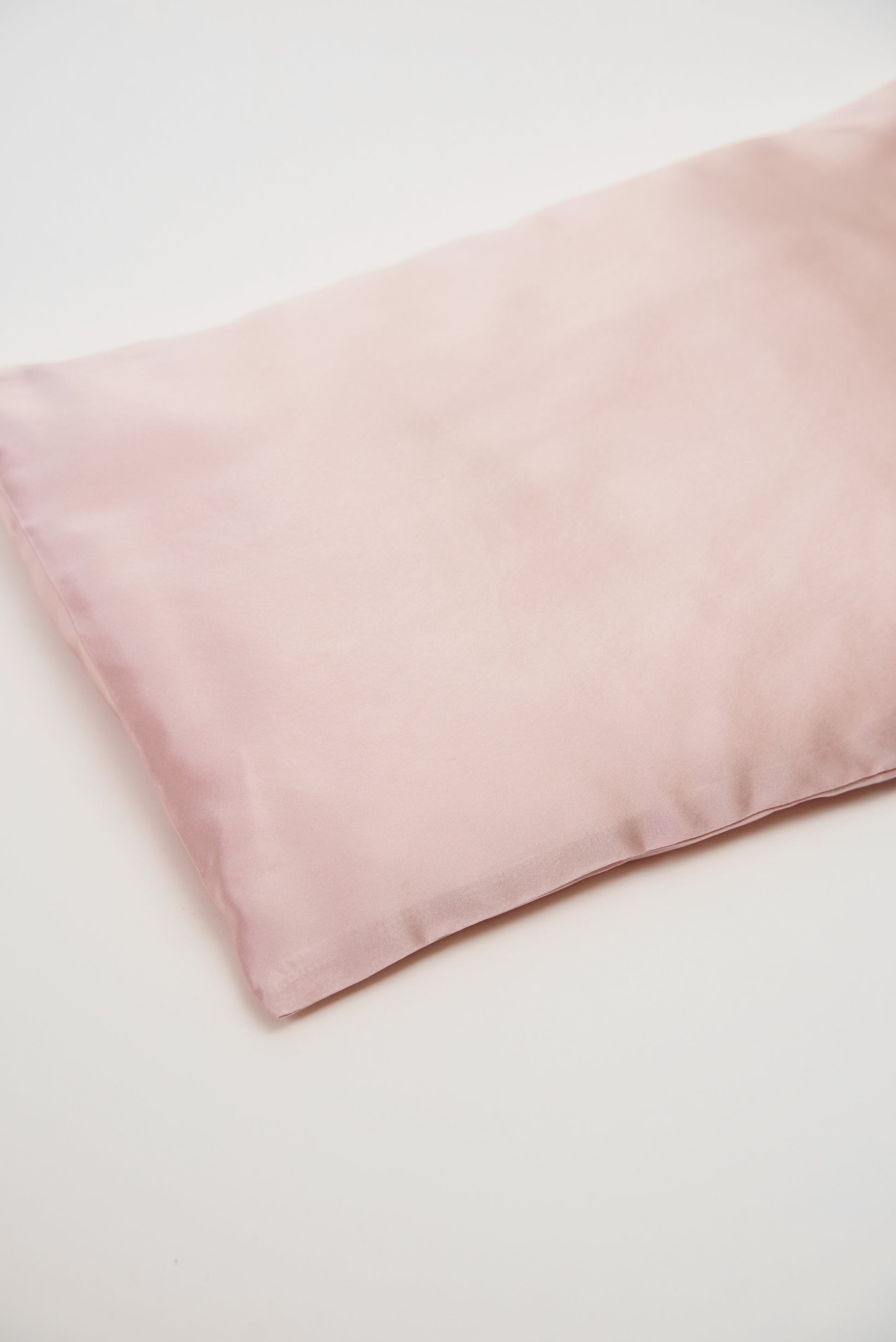 Close-up of premium 6A silk texture on a baby pink pillow, ultra-soft, breathable and eco-friendly.