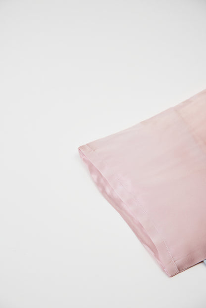 Close-up of premium 6A silk texture on a baby pink pillow, ultra-soft, breathable and eco-friendly.