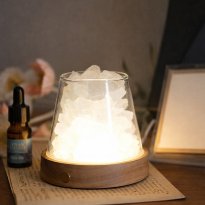 Glass lamp with wooden base emitting a warm glow on a surface with a blurred background