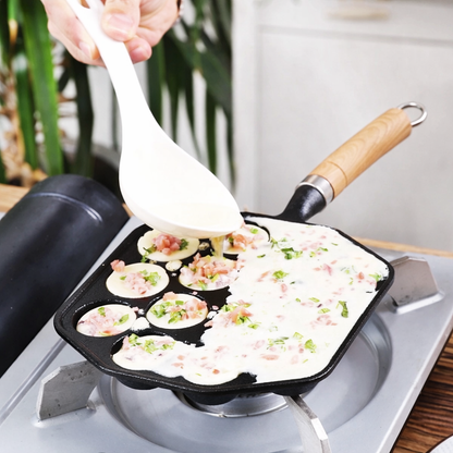 Person using a spatula to cook food in a non-stick pan on a stove.