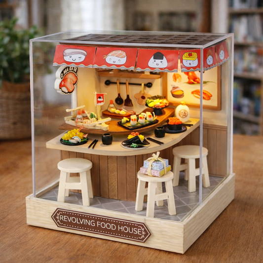 Model of a revolving food house with a transparent canopy displaying various food items on a wooden base.