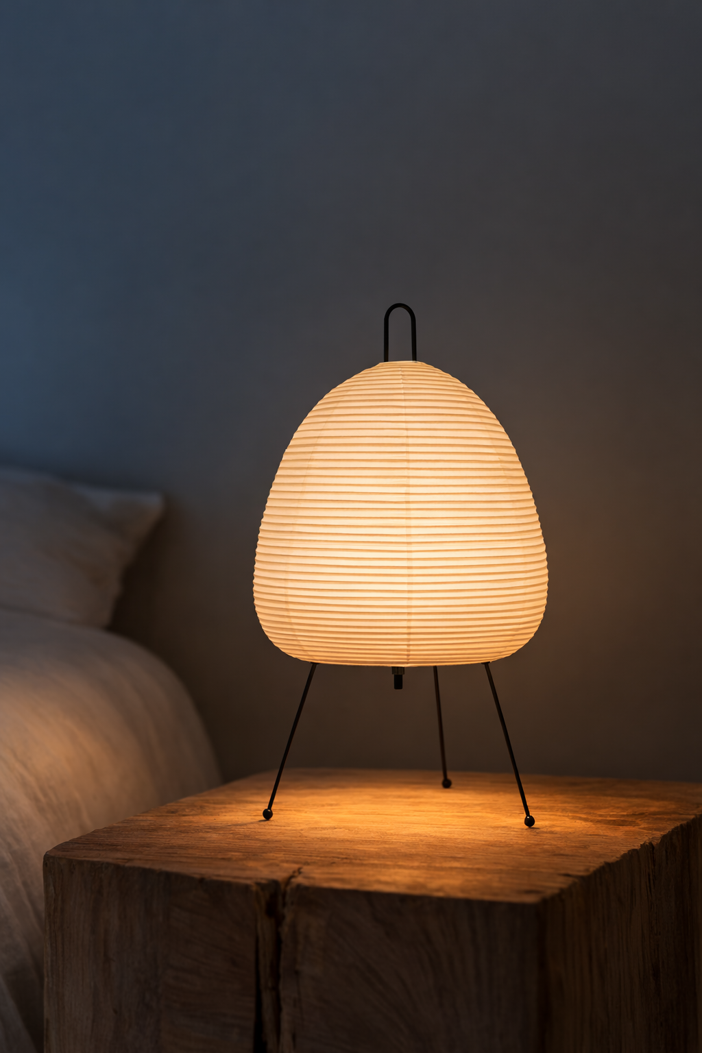 Table lamp with a warm glow on a wooden surface against a dark wall.