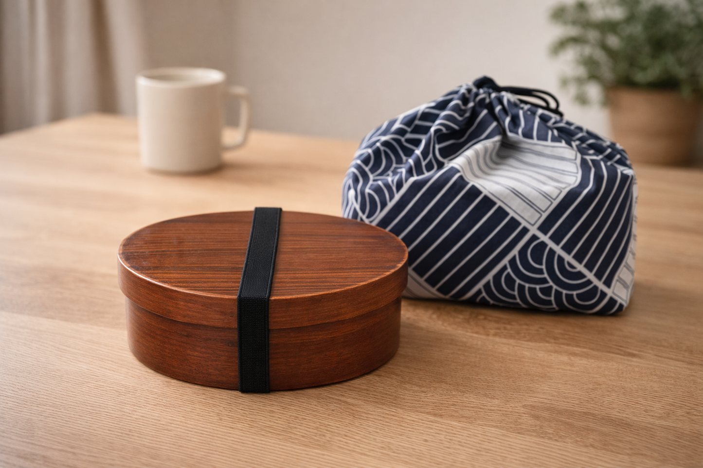 Wooden bento box with a black strap on a wooden table, next to a blue and white striped fabric bag.