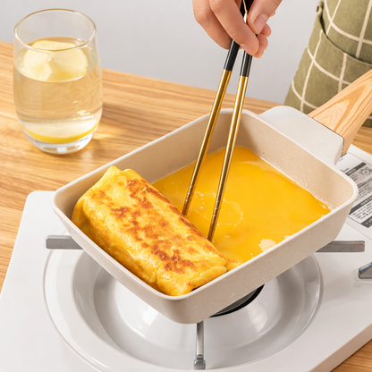 Person dipping a piece of fried food into a bowl of yellow sauce using chopsticks on a wooden table.