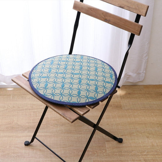 Round Japanese tatami chair pad made from natural igusa rush grass, vegan and sustainable, styled on a wooden chair with traditional geometric pattern.