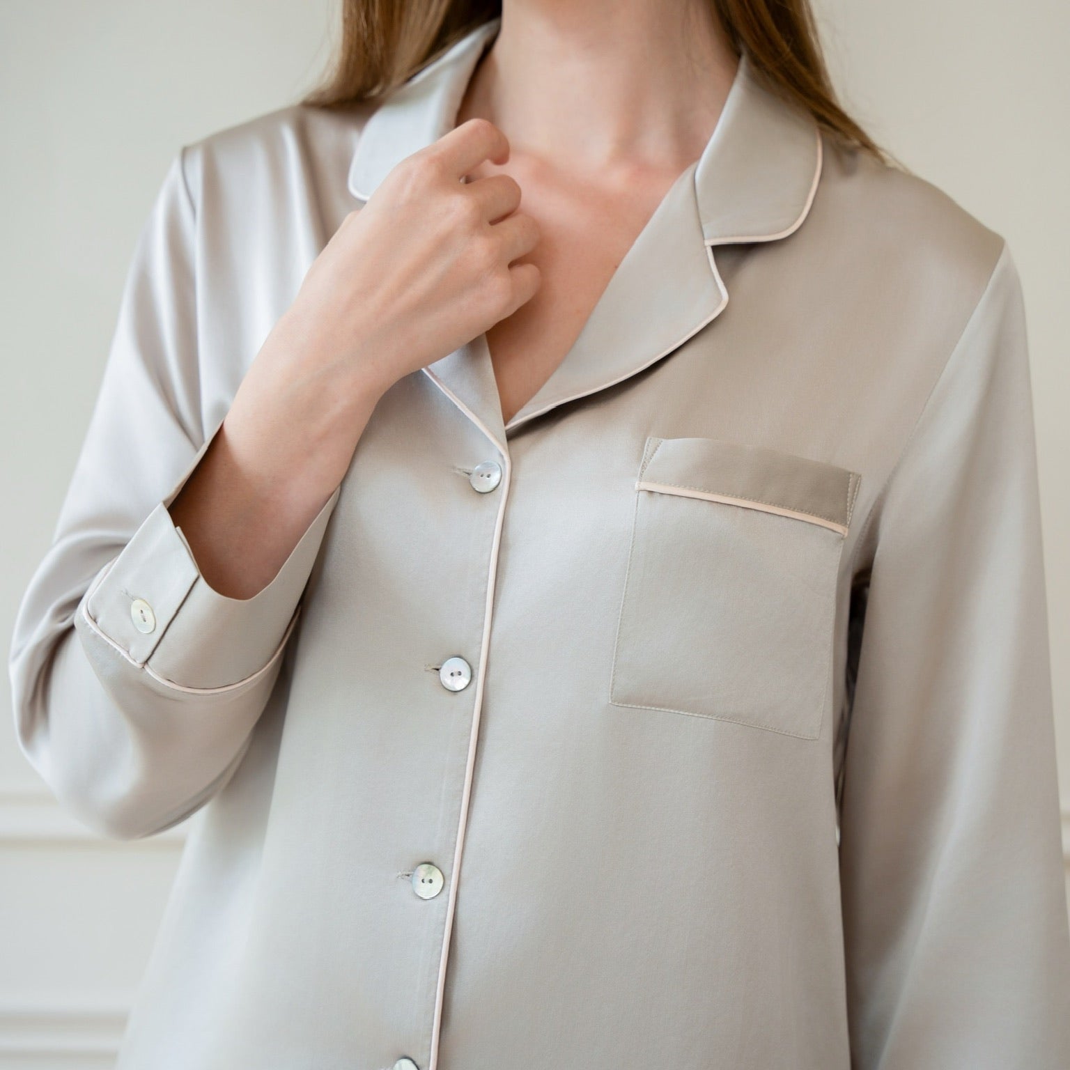 Close-up of a model wearing a silver grey Bebe Silk pajama top with cream piping