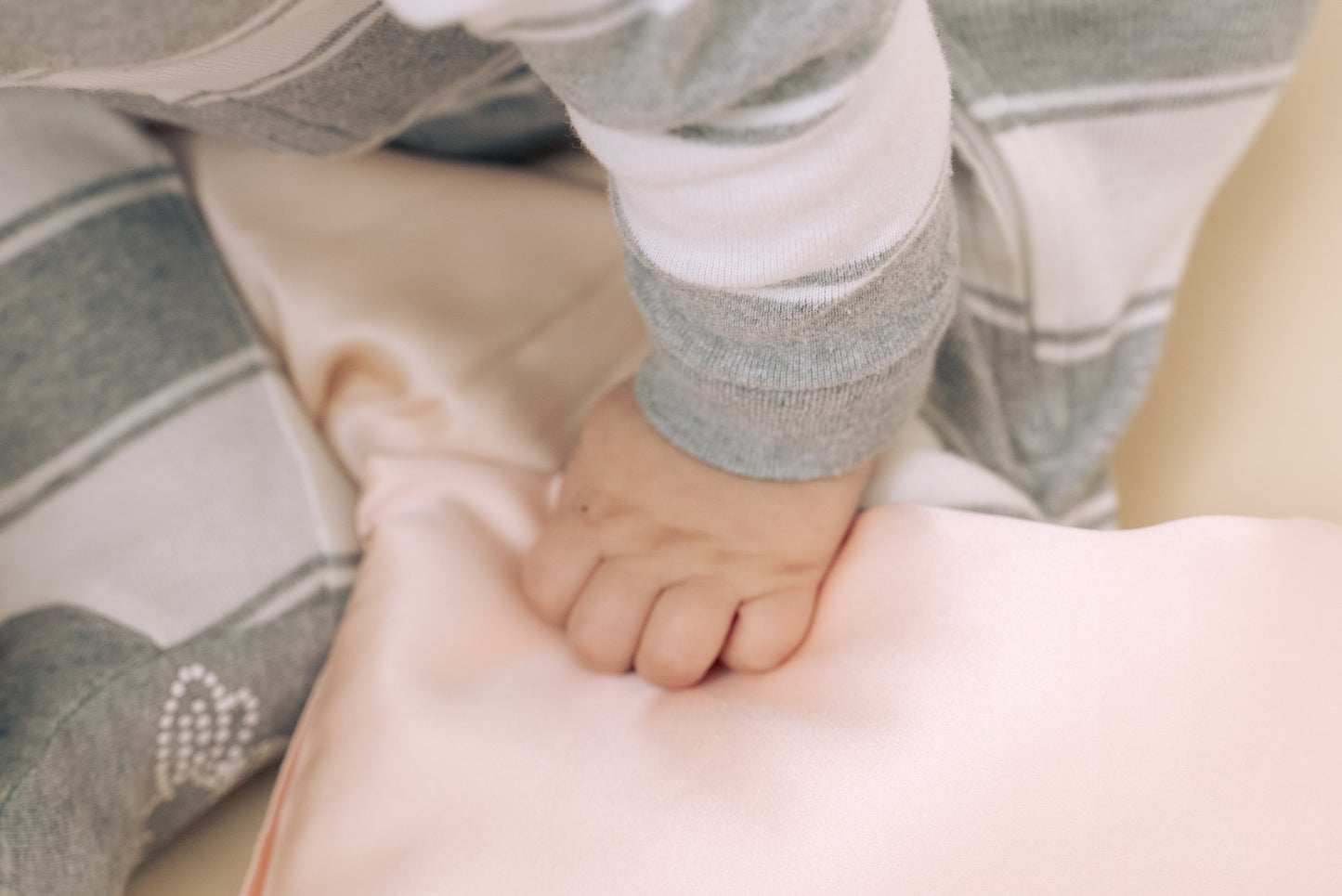 Close-up of premium 6A silk texture on a baby pink pillow, ultra-soft, breathable and eco-friendly.