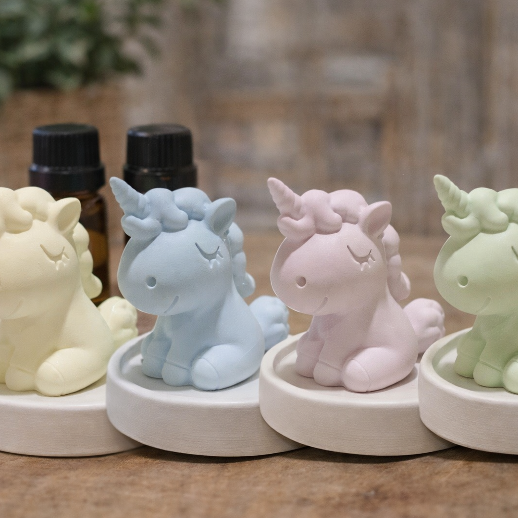 Four pastel-colored unicorn figurines on white bases with a blurred background.
