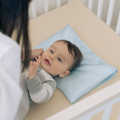 Premium 6A silk baby pillow in baby blue styled on a cozy nursery bed, smooth, breathable, vegan and sustainable.