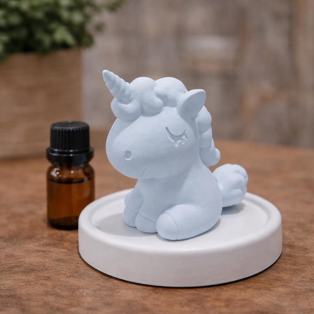 White unicorn figurine on a round base with a small bottle of essential oil in the background.