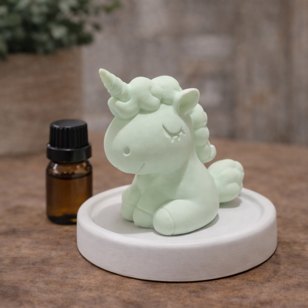Mint green unicorn-shaped diffuser on a wooden surface with a small bottle in the background.