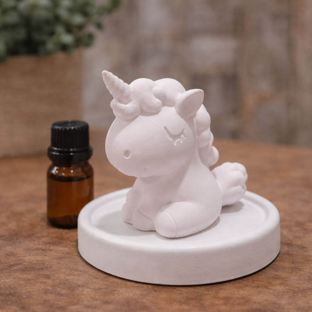 White unicorn figurine on a round base with a small bottle of essential oil in the background.