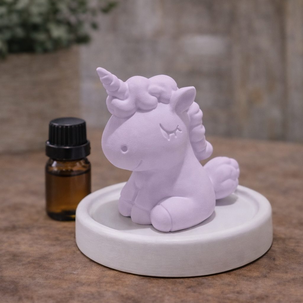 Unicorn-shaped diffuser on a stone surface with a bottle of essential oil in the background.