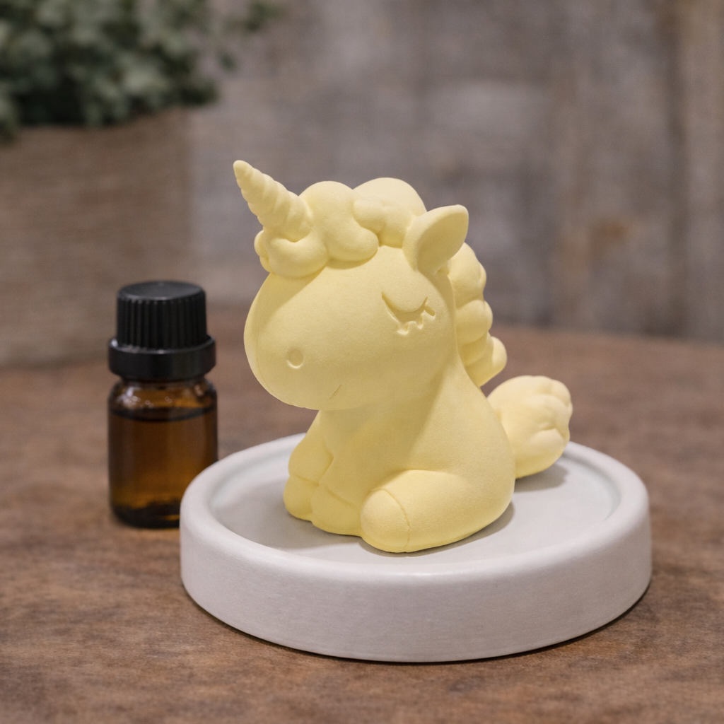Yellow unicorn candle on a white base with an amber bottle in the background